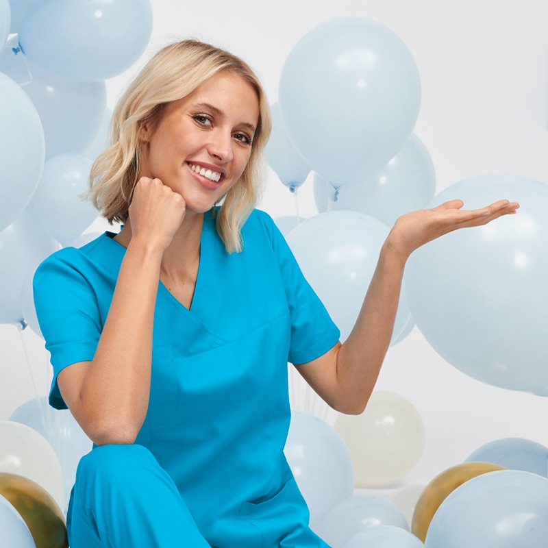 Frau in hellblauem Kasack und Luftballons zum Jubiläum