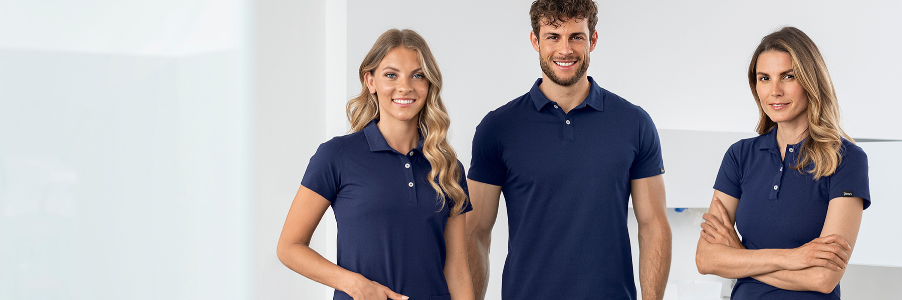 Ein Mann und zwei Frauen in blauen Poloshirts in einer Praxis